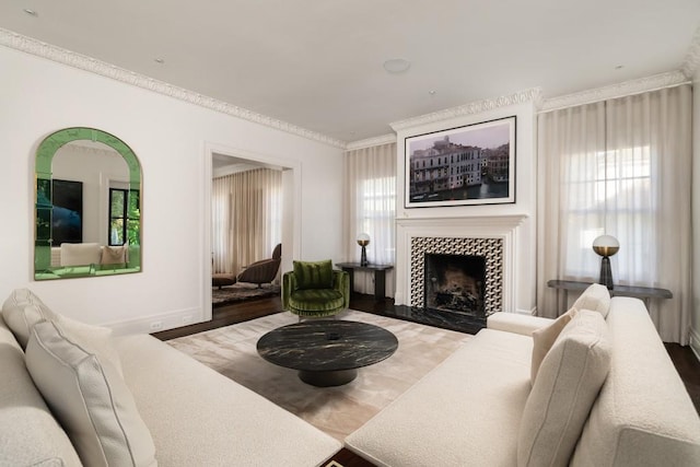 living room featuring wood-type flooring, ornamental molding, and a tiled fireplace