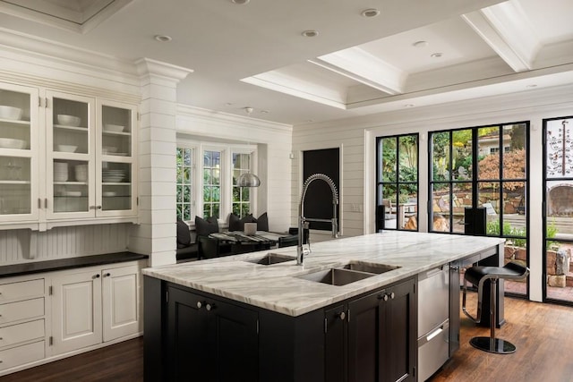 kitchen featuring white cabinets, an island with sink, a breakfast bar, and a healthy amount of sunlight