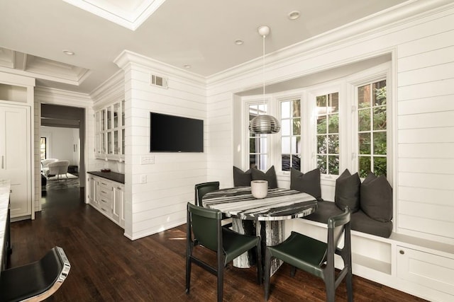 dining room featuring ornamental molding, wood walls, and dark wood-type flooring