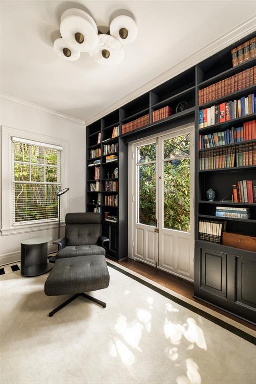 sitting room featuring built in shelves, ornamental molding, and a wealth of natural light