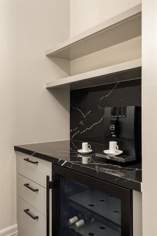 interior space with dark stone countertops, beverage cooler, decorative backsplash, and white cabinetry