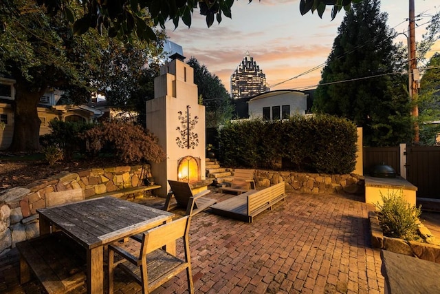 patio terrace at dusk featuring exterior fireplace