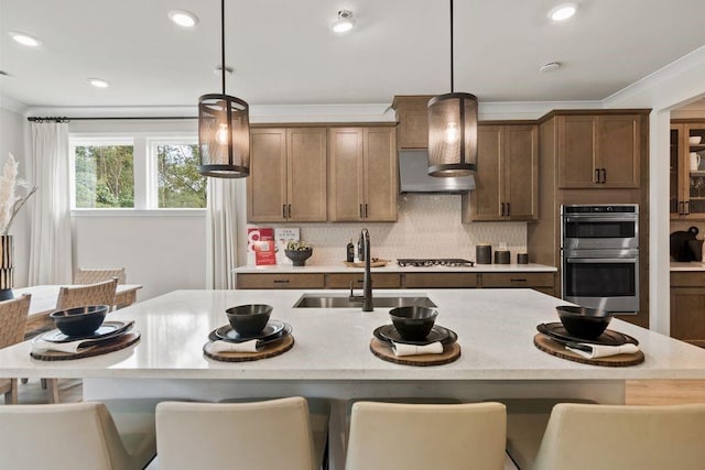 kitchen featuring appliances with stainless steel finishes, crown molding, sink, pendant lighting, and a breakfast bar area