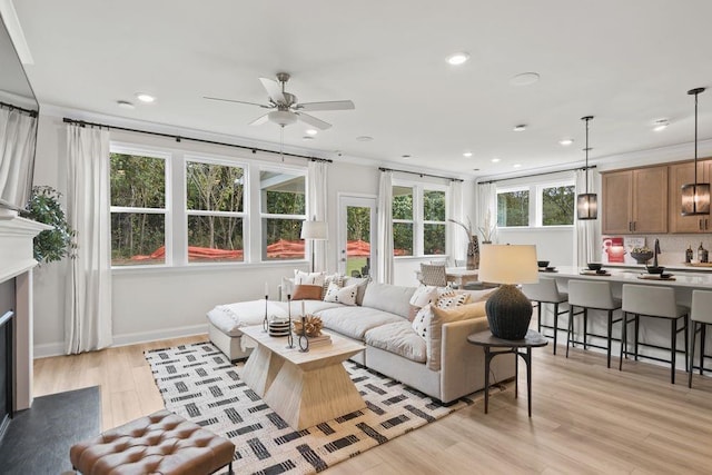 living room featuring light hardwood / wood-style flooring, ceiling fan, and ornamental molding