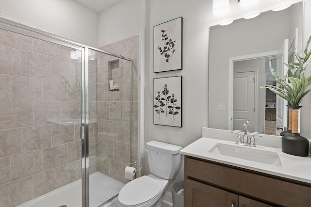 bathroom with vanity, a shower with shower door, and toilet