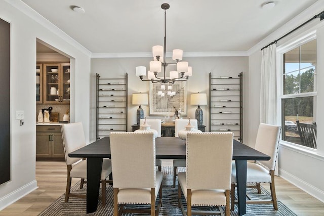 dining area with ornamental molding, light hardwood / wood-style flooring, and an inviting chandelier