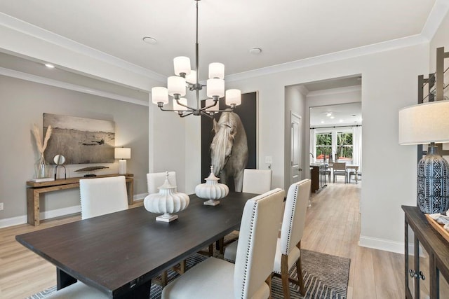 dining room with ornamental molding, light wood-type flooring, and a notable chandelier