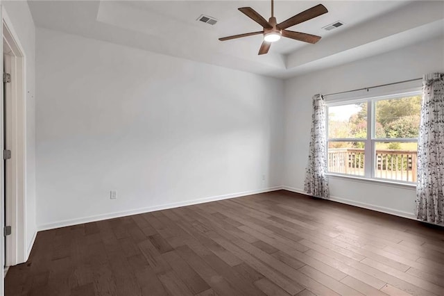 spare room with a raised ceiling, dark hardwood / wood-style floors, and ceiling fan