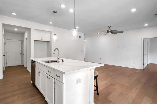 kitchen with white cabinets, a kitchen island with sink, dark wood-type flooring, decorative light fixtures, and sink