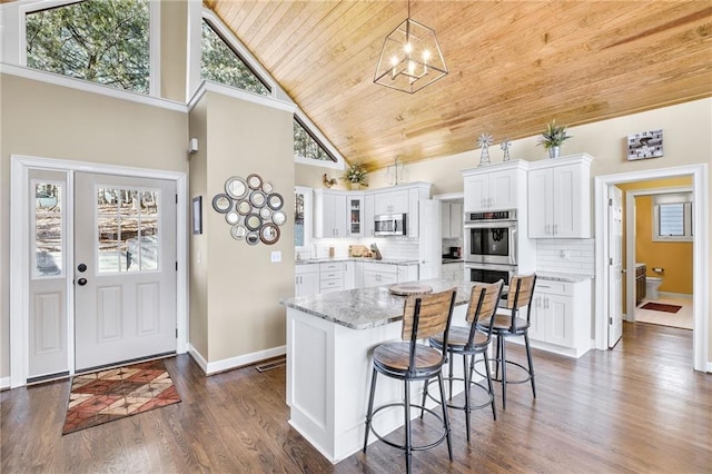 kitchen with wooden ceiling, dark wood-type flooring, white cabinets, appliances with stainless steel finishes, and tasteful backsplash