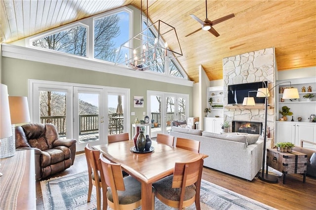 dining room featuring french doors, a fireplace, wood finished floors, high vaulted ceiling, and wooden ceiling