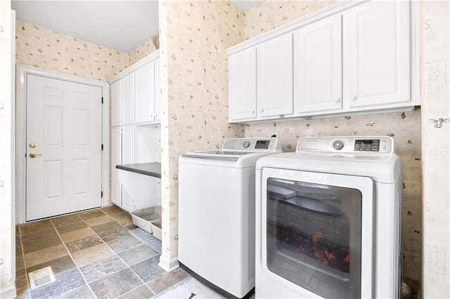 laundry room with washer and dryer, cabinet space, and wallpapered walls