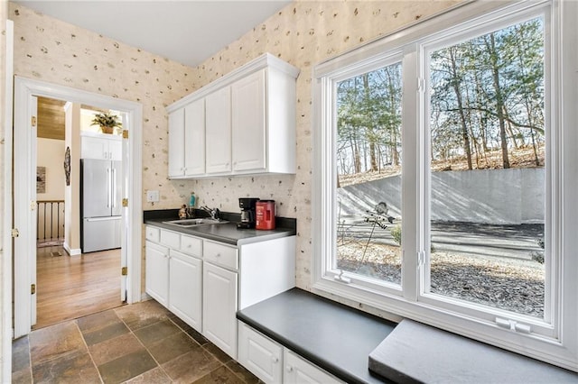 kitchen featuring dark countertops, high end refrigerator, a wealth of natural light, and wallpapered walls