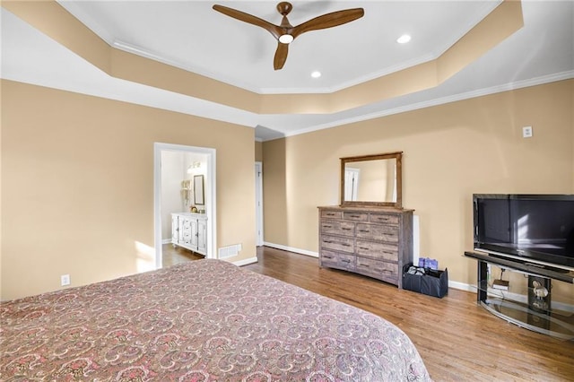 bedroom with baseboards, ornamental molding, wood finished floors, a tray ceiling, and recessed lighting