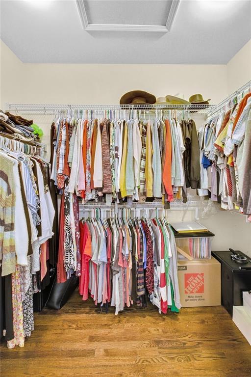 walk in closet featuring attic access and wood finished floors