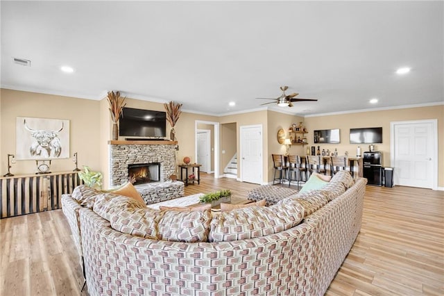 living room with stairway, a fireplace, light wood-style flooring, and ornamental molding