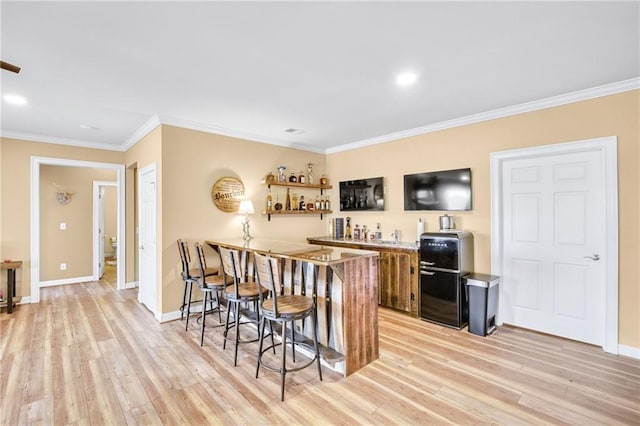 bar featuring baseboards, crown molding, light wood-style flooring, and a dry bar