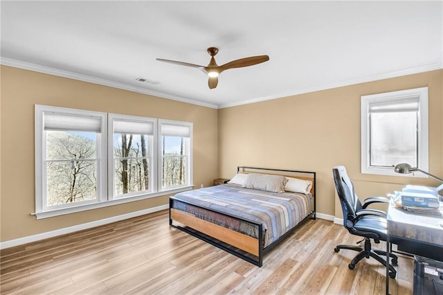 bedroom with light wood finished floors, baseboards, visible vents, ceiling fan, and crown molding