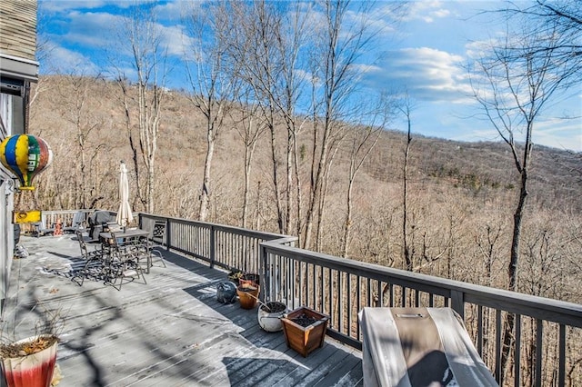 wooden deck featuring a view of trees and outdoor dining space