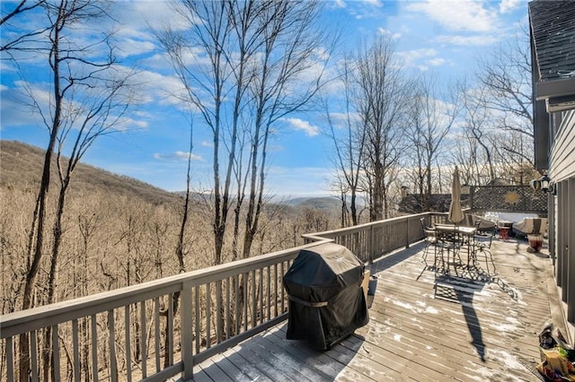 wooden terrace with a grill and outdoor dining area