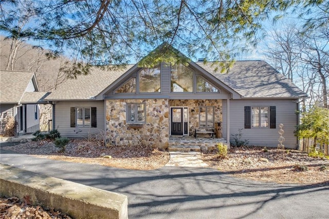 view of front of house featuring stone siding and roof with shingles