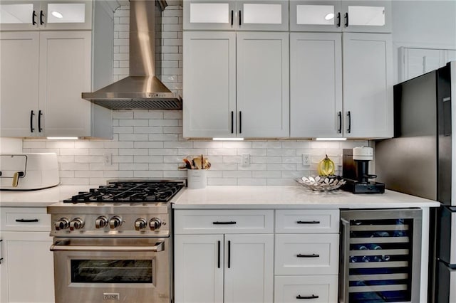3355 Olivia Ct, Cumming, GA 30041 - kitchen with wall chimney exhaust hood, wine cooler, high end stove, freestanding refrigerator, and white cabinets