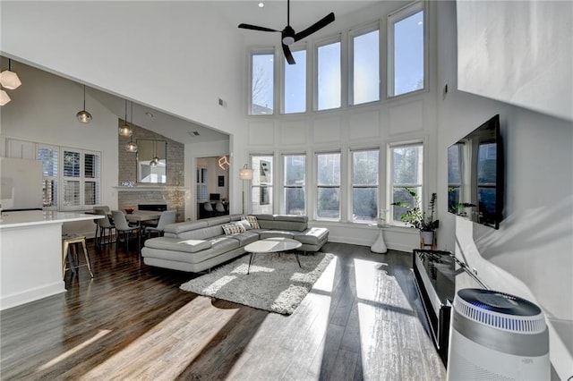 3355 Olivia Ct, Cumming, GA 30041 - living room featuring a towering ceiling, healthy amount of natural light, a ceiling fan, dark wood-style flooring, and a fireplace