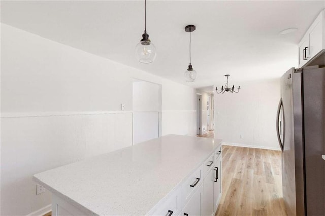 kitchen with white cabinetry, hanging light fixtures, a center island, and stainless steel refrigerator