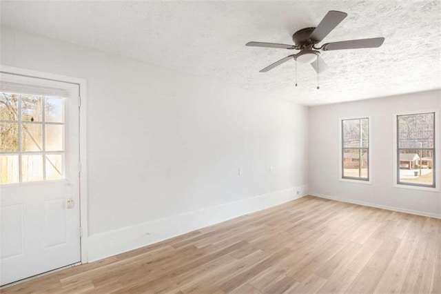 empty room with a textured ceiling, light hardwood / wood-style flooring, and ceiling fan