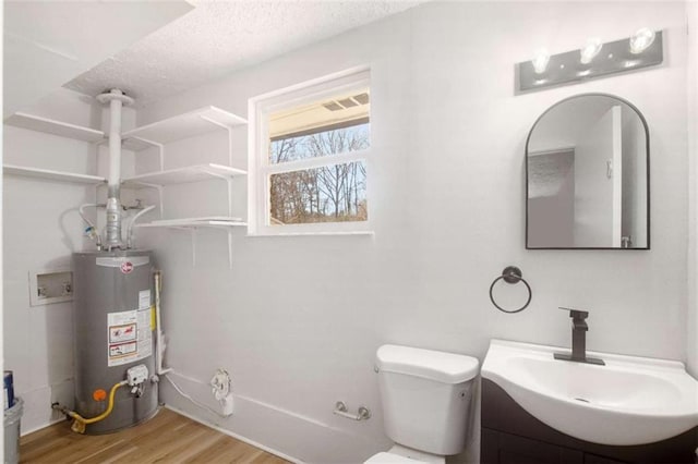 bathroom with a textured ceiling, water heater, wood-type flooring, vanity, and toilet