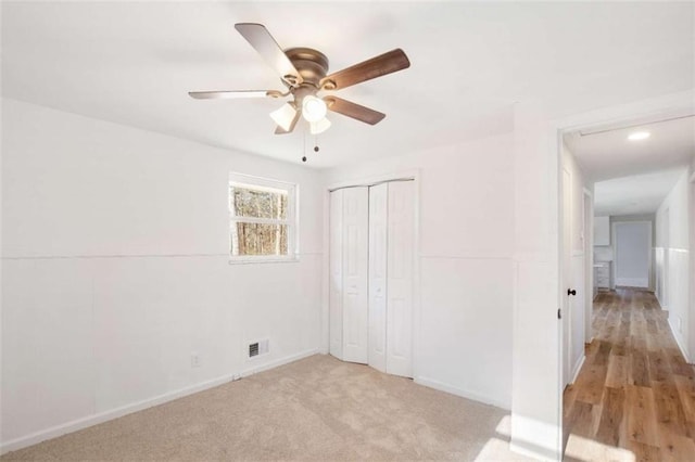 unfurnished bedroom with light carpet, a closet, and ceiling fan