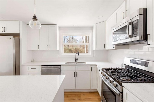 kitchen with sink, white cabinets, light hardwood / wood-style floors, and stainless steel appliances