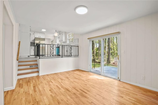 unfurnished room with stairway, baseboards, and light wood-type flooring