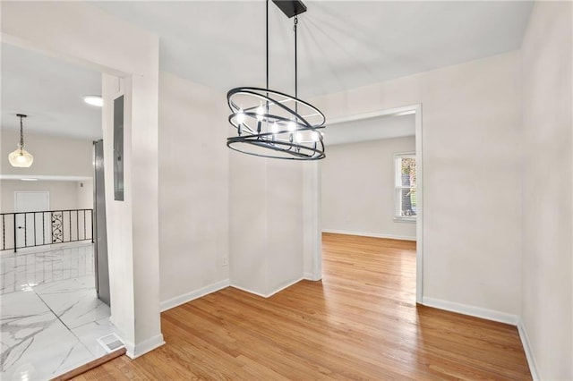 unfurnished dining area featuring visible vents, light wood-style flooring, baseboards, and an inviting chandelier