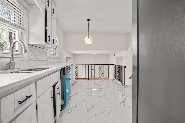 kitchen with a sink, marble finish floor, white cabinets, and dishwasher