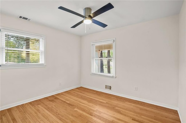 spare room featuring visible vents, a healthy amount of sunlight, light wood-style flooring, and baseboards