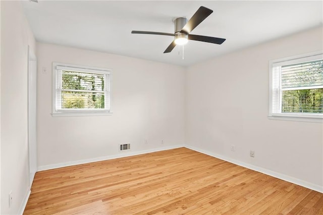 empty room with visible vents, a healthy amount of sunlight, and light wood finished floors