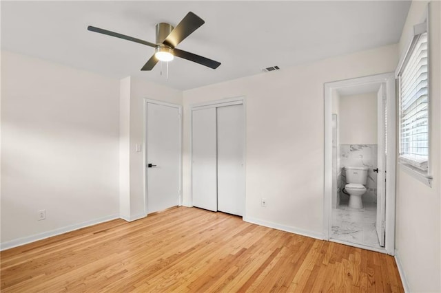 unfurnished bedroom with visible vents, light wood-style flooring, ensuite bathroom, a closet, and ceiling fan