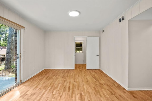 empty room with visible vents, light wood-style flooring, and baseboards