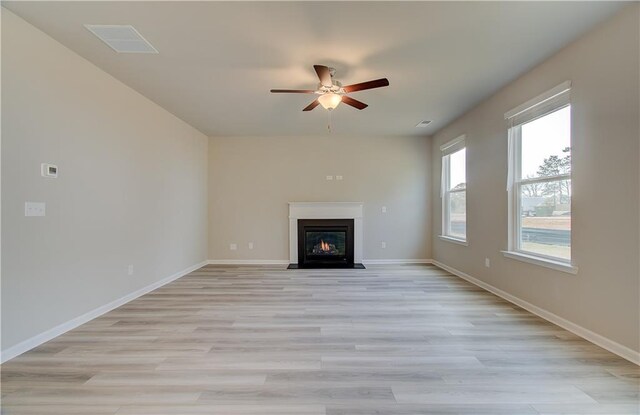 138 Crabbswood Dr, Mcdonough, GA 30253 - unfurnished living room with a fireplace with flush hearth, baseboards, light wood finished floors, visible vents, and a ceiling fan