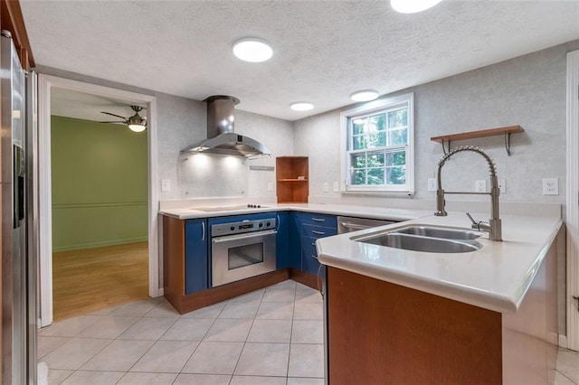 kitchen featuring a textured ceiling, light hardwood / wood-style flooring, island range hood, blue cabinets, and appliances with stainless steel finishes