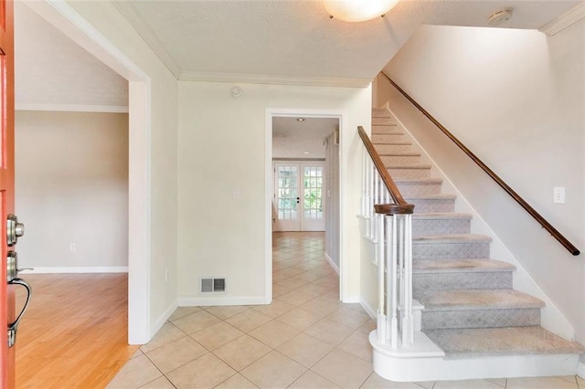 stairway featuring french doors, wood-type flooring, and ornamental molding