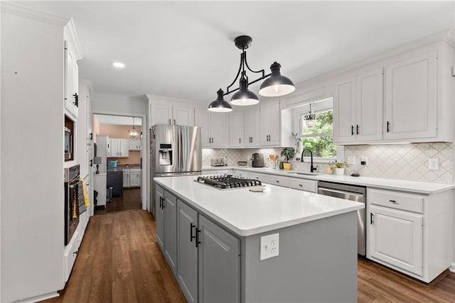 kitchen featuring a kitchen island, decorative light fixtures, white cabinetry, stainless steel appliances, and sink