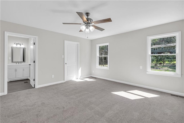 unfurnished bedroom featuring baseboards, visible vents, ensuite bathroom, carpet floors, and a sink