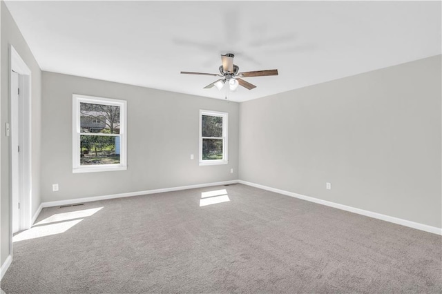 carpeted spare room featuring a ceiling fan, visible vents, and baseboards