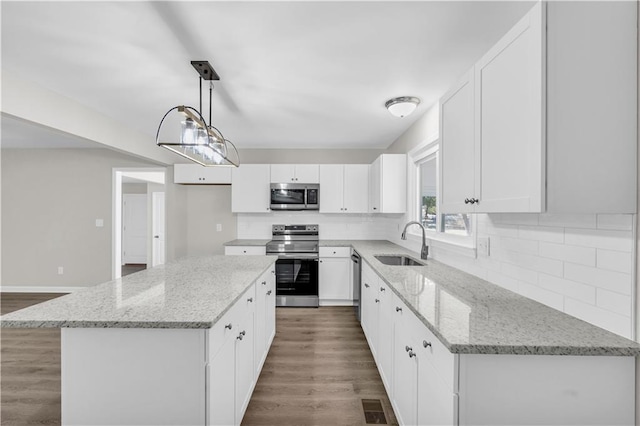 kitchen with stainless steel appliances, wood finished floors, a sink, visible vents, and backsplash