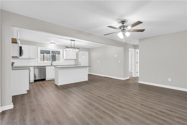 kitchen with baseboards, dark wood finished floors, dishwasher, a center island, and white cabinetry