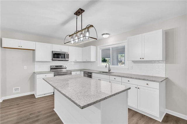 kitchen featuring appliances with stainless steel finishes, a center island, white cabinets, and a sink