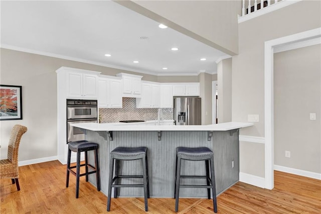 kitchen with appliances with stainless steel finishes, a kitchen breakfast bar, and white cabinets