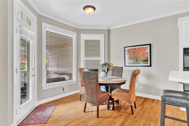 dining space featuring light wood-style floors, baseboards, and ornamental molding